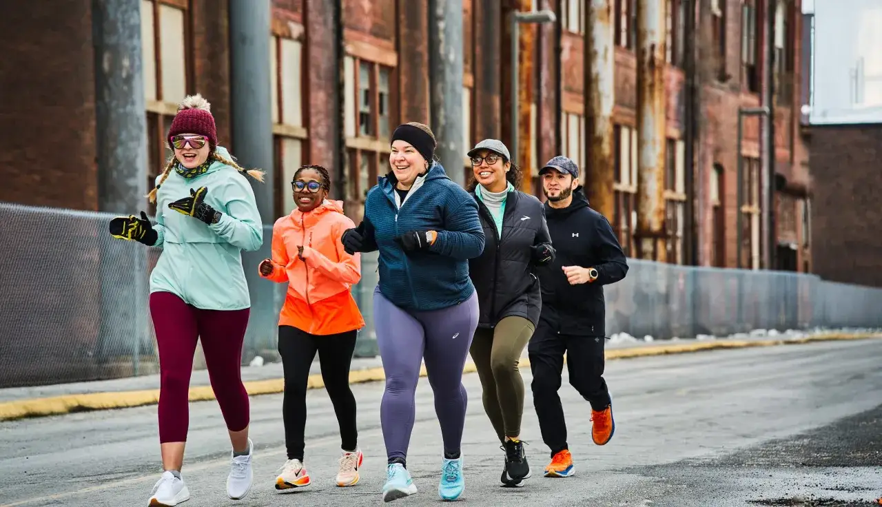 F&uuml;nf L&auml;uferinnen und ein L&auml;ufer joggen fr&ouml;hlich nebeneinander. Sie trainieren, um zu sehen, wie oft sie joggen in der Woche k&ouml;nnen.