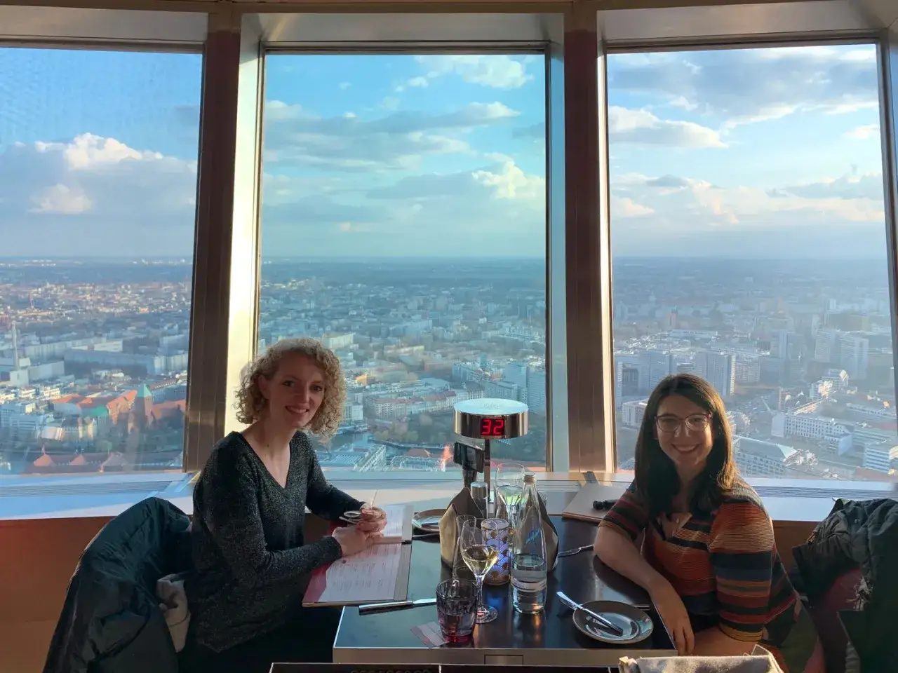 Zwei Frauen genie&szlig;en den Blick &uuml;ber Berlin bei Sonnenuntergang. Die Spree funkelt in der Ferne.