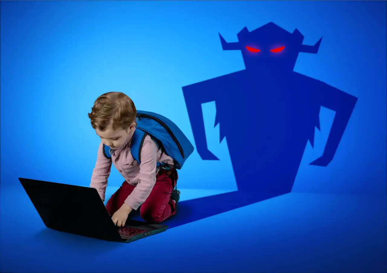 Chłopiec z plecakiem przy laptopie, a za nim cień potwora. Przypomnienie o zasadach bezpiecznego korzystania z internetu dla dzieci.