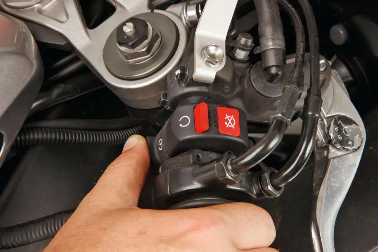 Dito, il motorino gira ma la moto non parte. Il pollice preme il pulsante di accensione sulla moto.