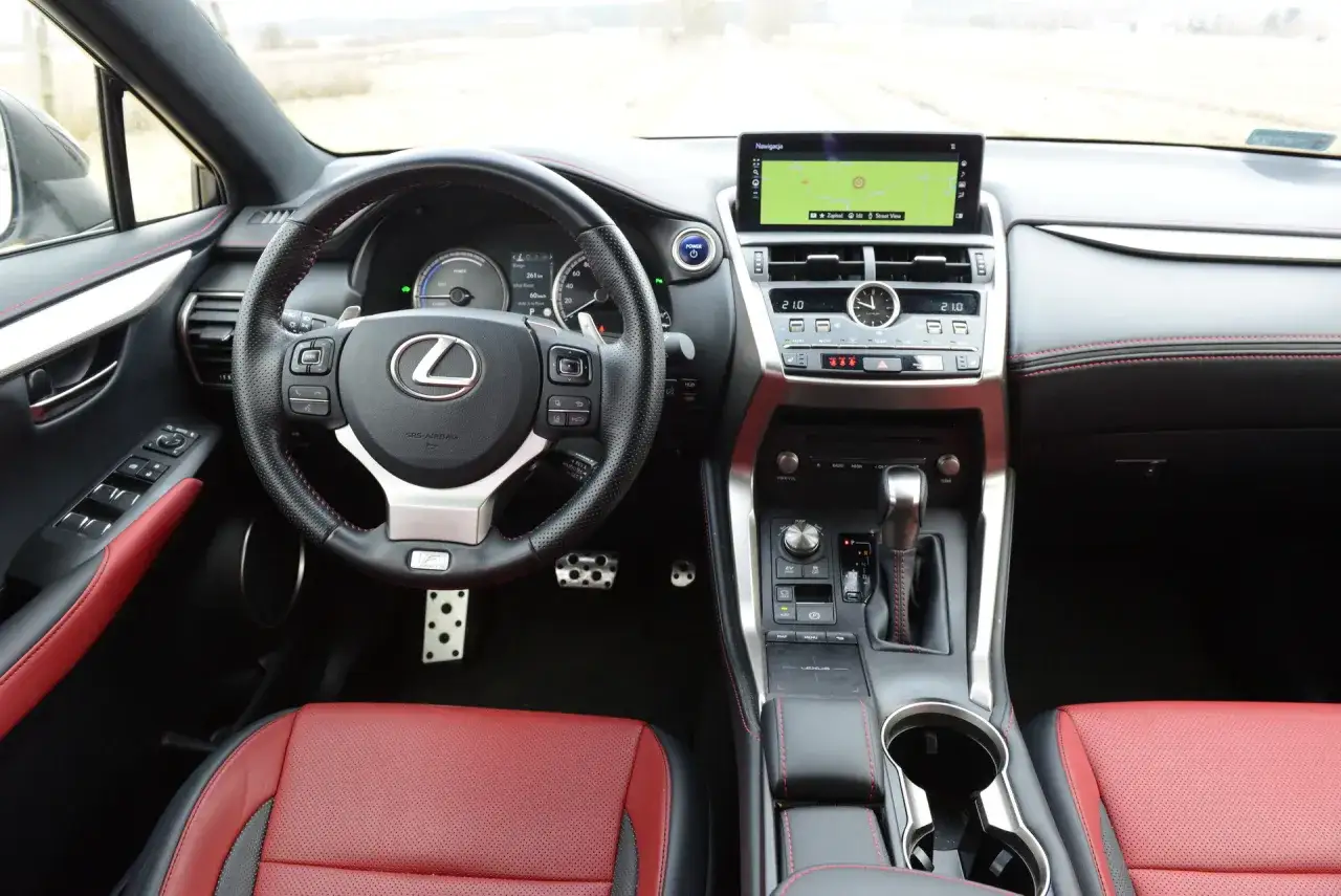 Wnętrze Lexus NX 2025 z czerwoną tapicerką, ekranem nawigacji i kierownicą.