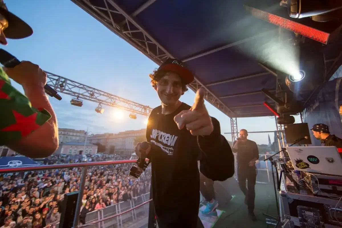 Młody raper z JWP Crew na koncercie, w wieku młodzieńczym, wskazuje palcem na widownię.