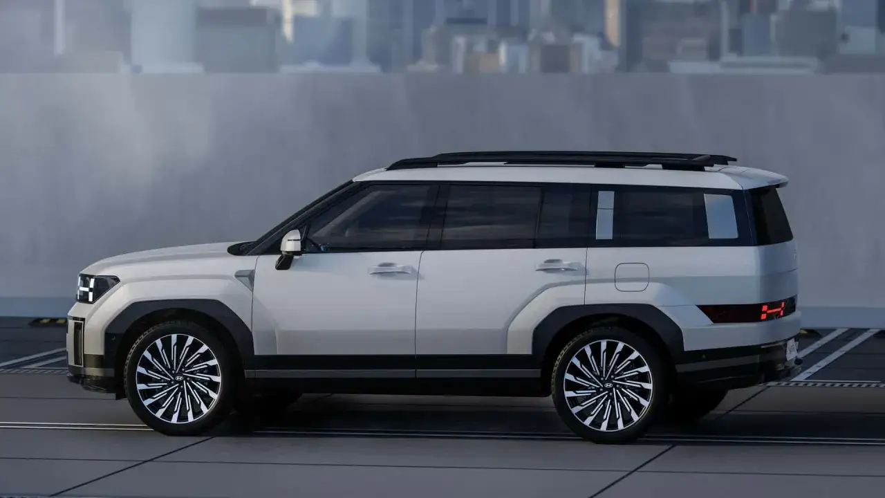 Nowy Hyundai Santa Fe 2025 w białym kolorze, z masywnymi nadkolami i futurystycznymi światłami, gotowy na miejskie wyzwania.