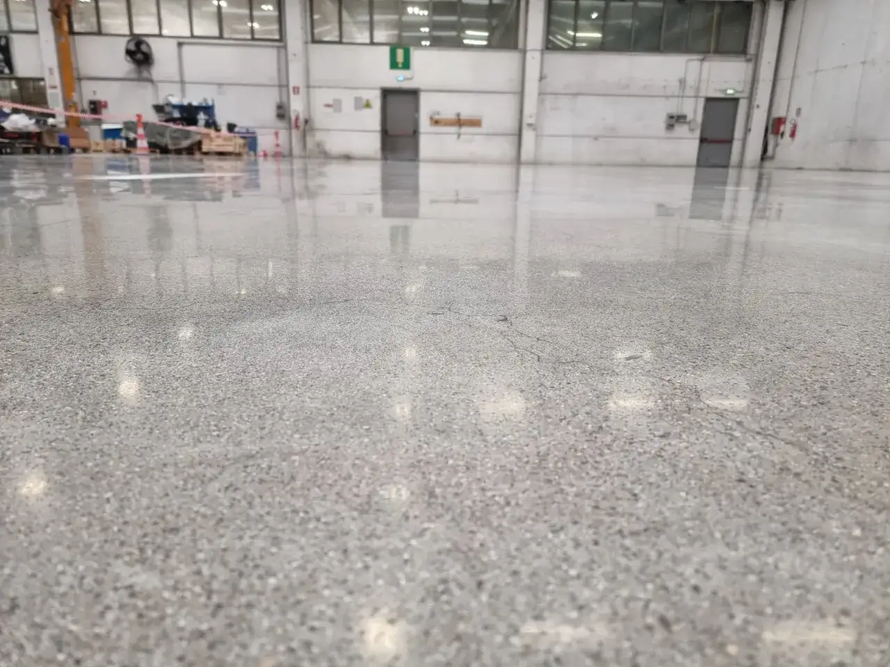 Pavimento industriale con finitura lucida, che mostra la differenza tra levigatura e lucidatura. Riflessi luminosi sul cemento levigato.