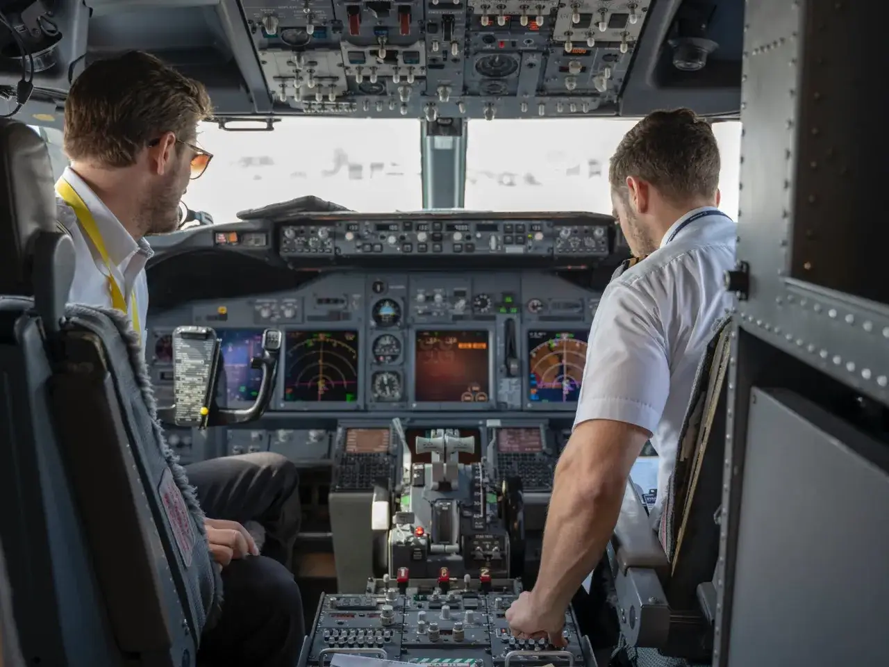 Dwóch pilotów w kokpicie samolotu. Jeden z nich patrzy na instrumenty, drugi obsługuje sterowanie. Ciekawe, ile zarabia pilot samolotu za taką odpowiedzialność.