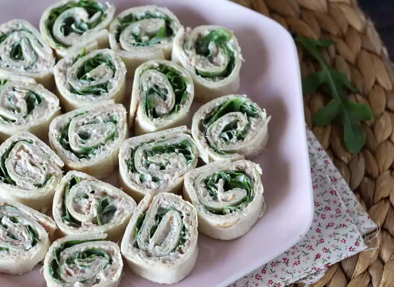 En rosa bricka full med l&auml;ckra tonfisk wrap-rullar, fyllda med kr&auml;mig tonfiskr&ouml;ra och gr&ouml;na blad. Perfekt f&ouml;r fest eller fika.