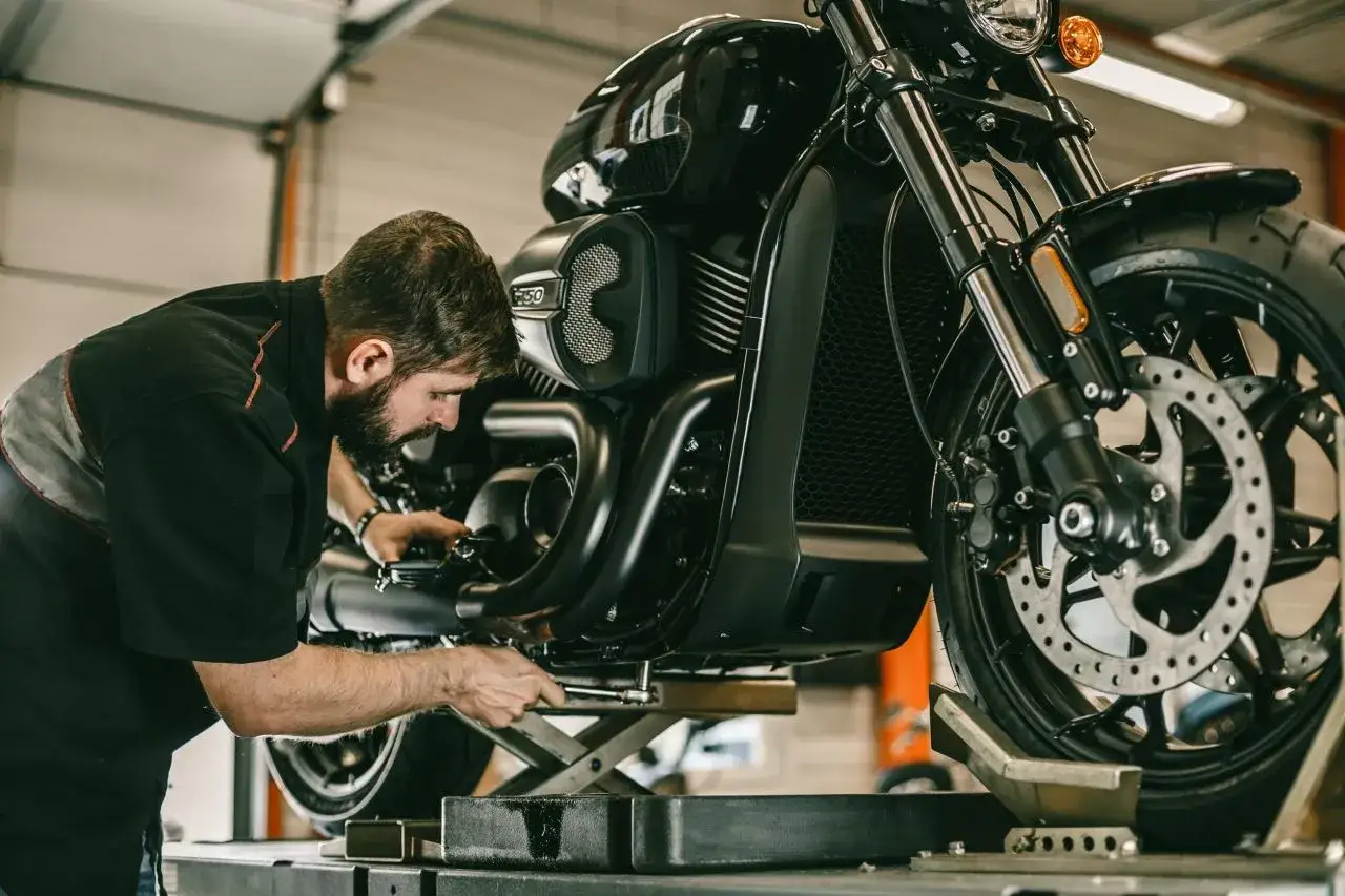 Meccanico al lavoro su una moto. Per sapere cambio olio moto ogni quanto, consulta il manuale.