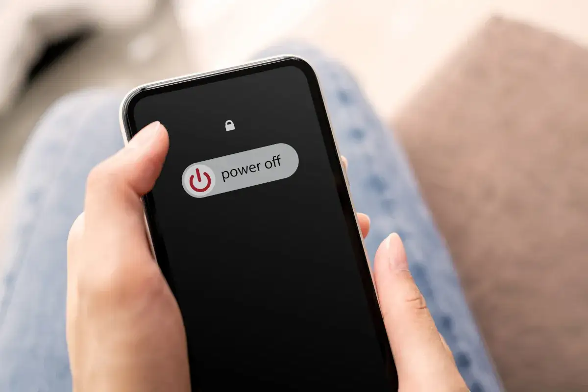 Dłoń trzyma smartfon z widocznym menu wyłączania. Dowiedz się, jak włączyć tryb awaryjny w telefonie, gdy coś idzie nie tak.