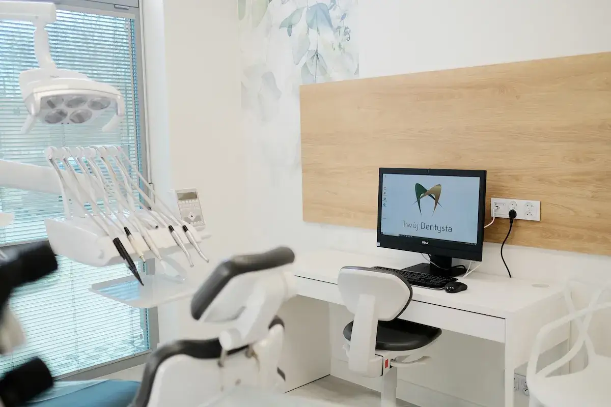 Nowoczesny gabinet stomatologiczny z fotelem dentystycznym, lampą i komputerem.