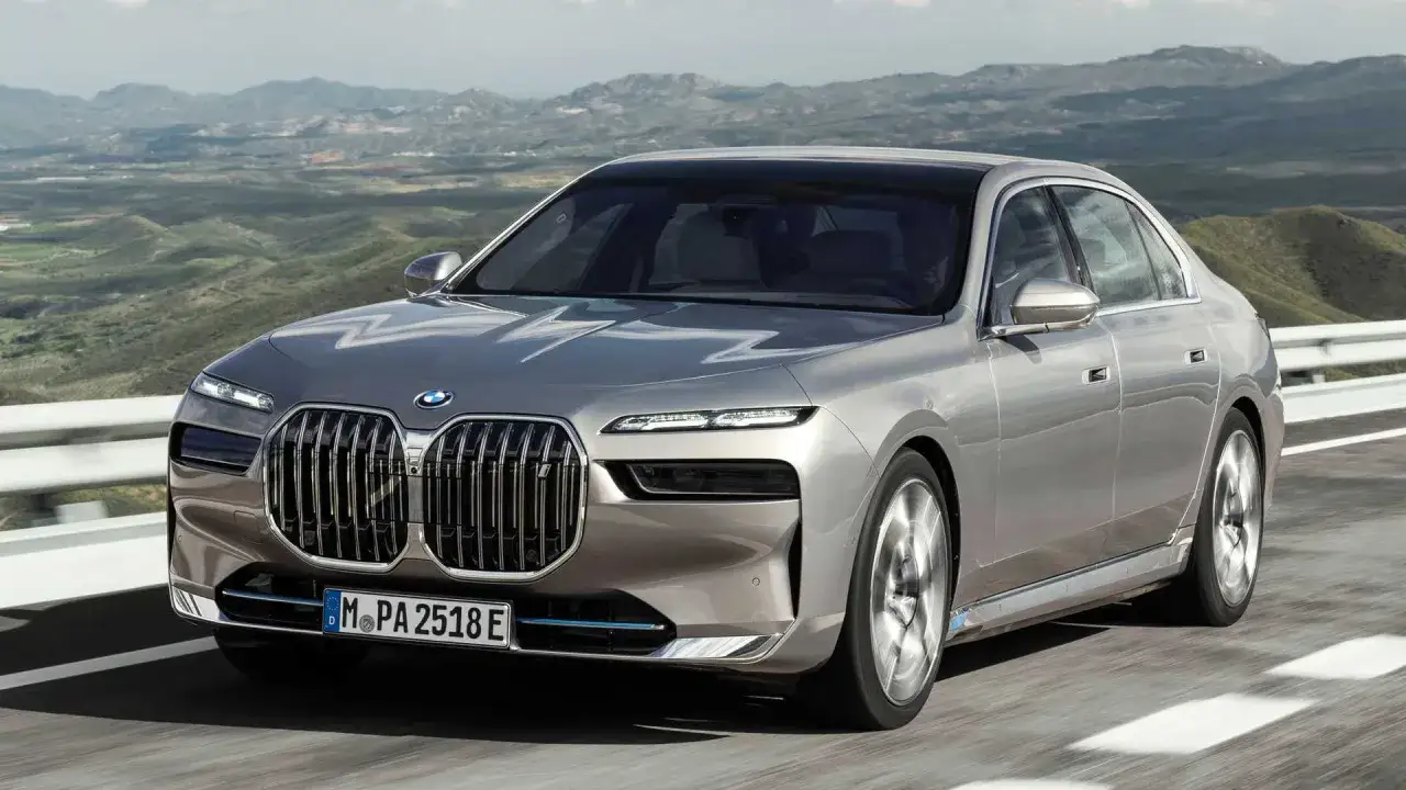Eleganckie BMW i7 w kolorze srebrnym przemierza malowniczą, górską drogę.