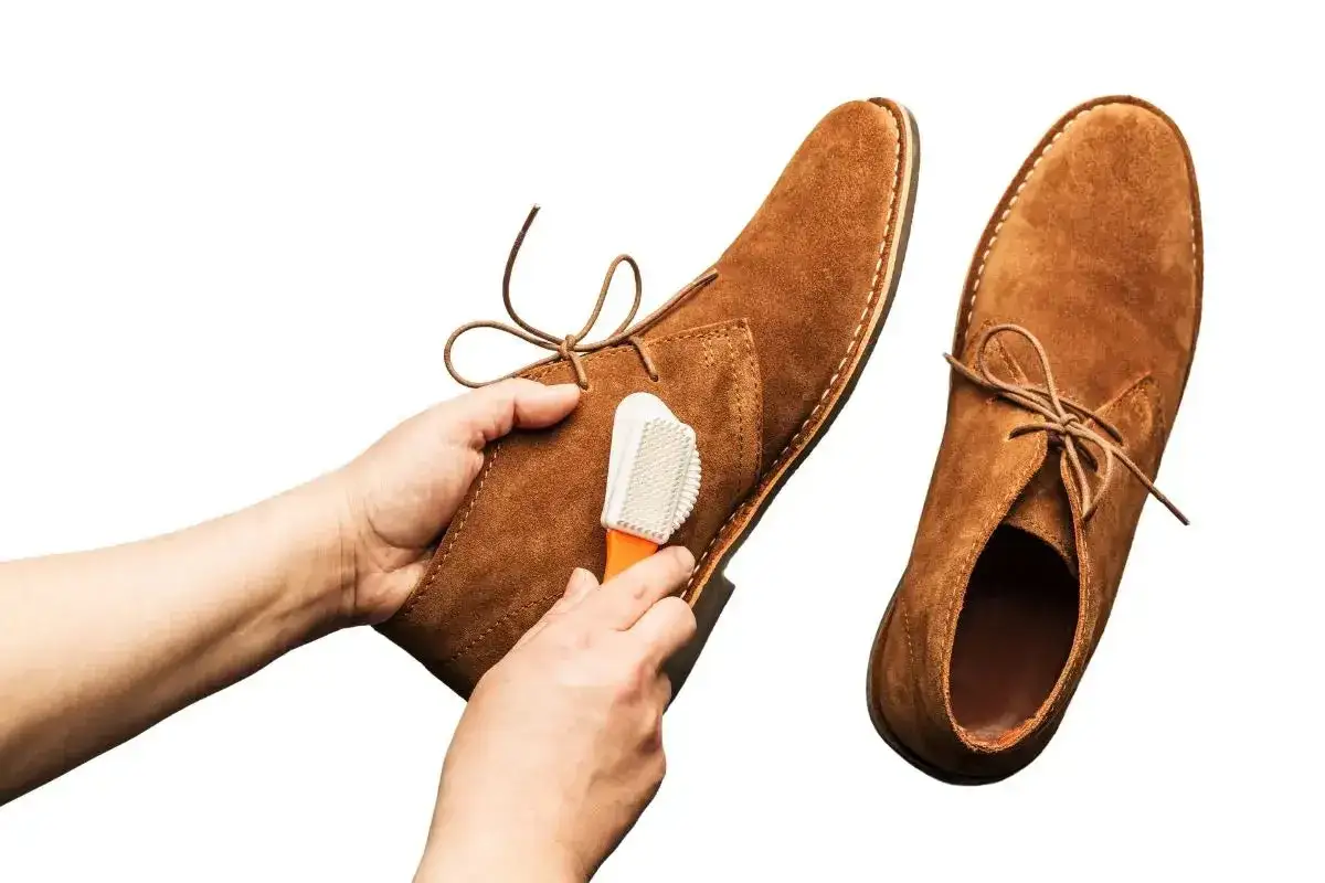 Nettoyage d'une chaussure en matière suède avec une brosse.