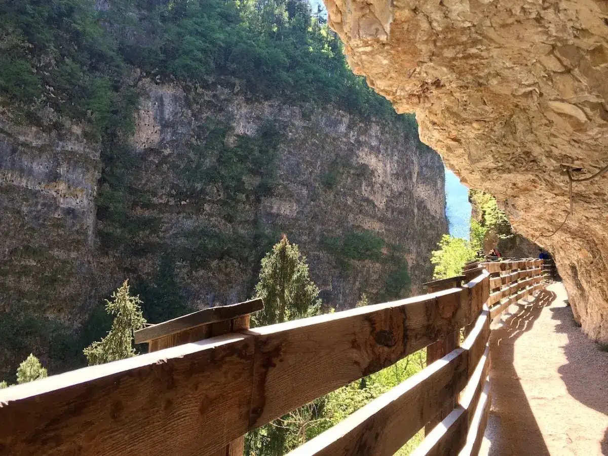 Sentiero panoramico con staccionata in legno lungo una gola rocciosa, verso San Romedio.