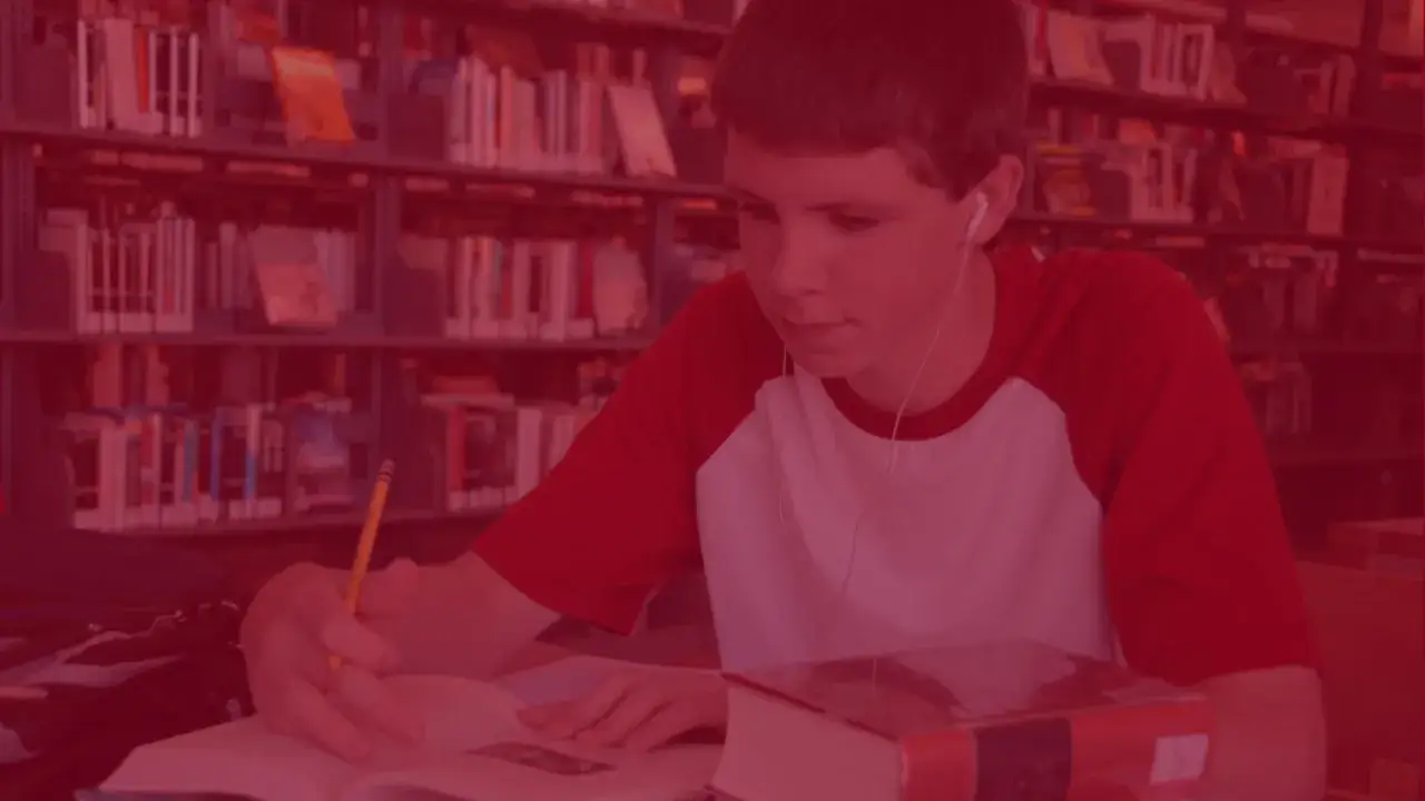 Chłopak w słuchawkach uczy się w bibliotece, przygotowując się do studiów zaocznych w Łodzi.