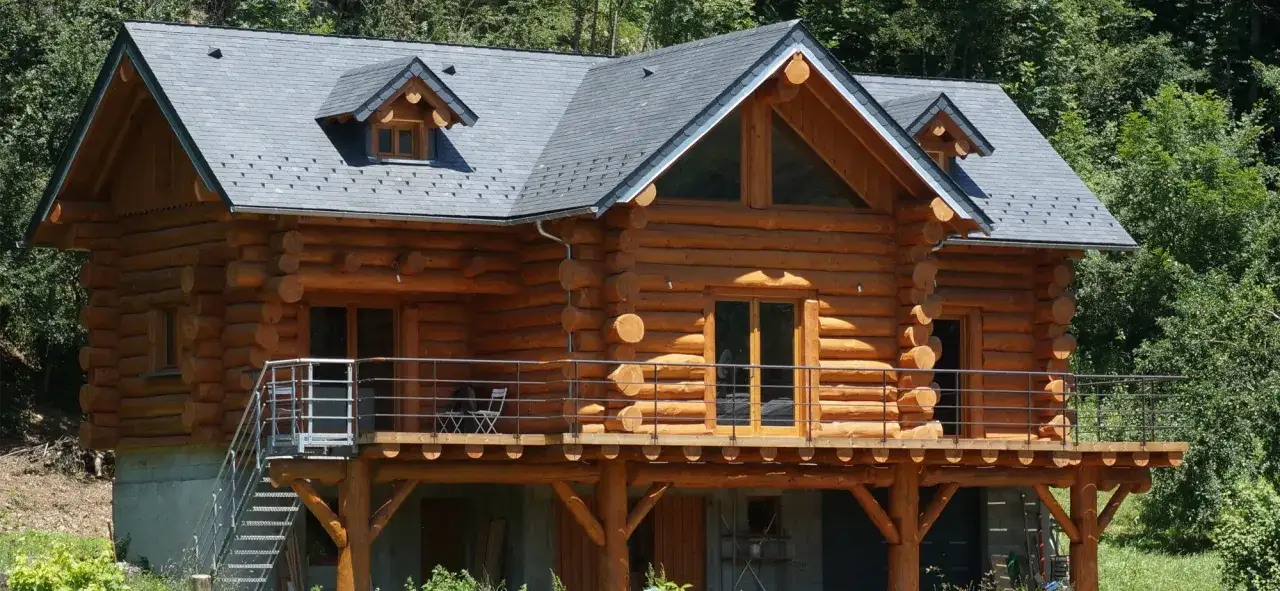 Magnifique maison en rondin de bois nich&eacute;e dans la verdure. Une terrasse en bois entoure cette demeure chaleureuse.