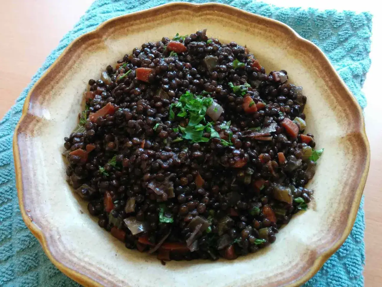 En sk&aring;l med belugalinser, mor&ouml;tter och l&ouml;k, perfekt f&ouml;r ett h&auml;lsosamt belugalinser recept. Garnerad med f&auml;rsk persilja.