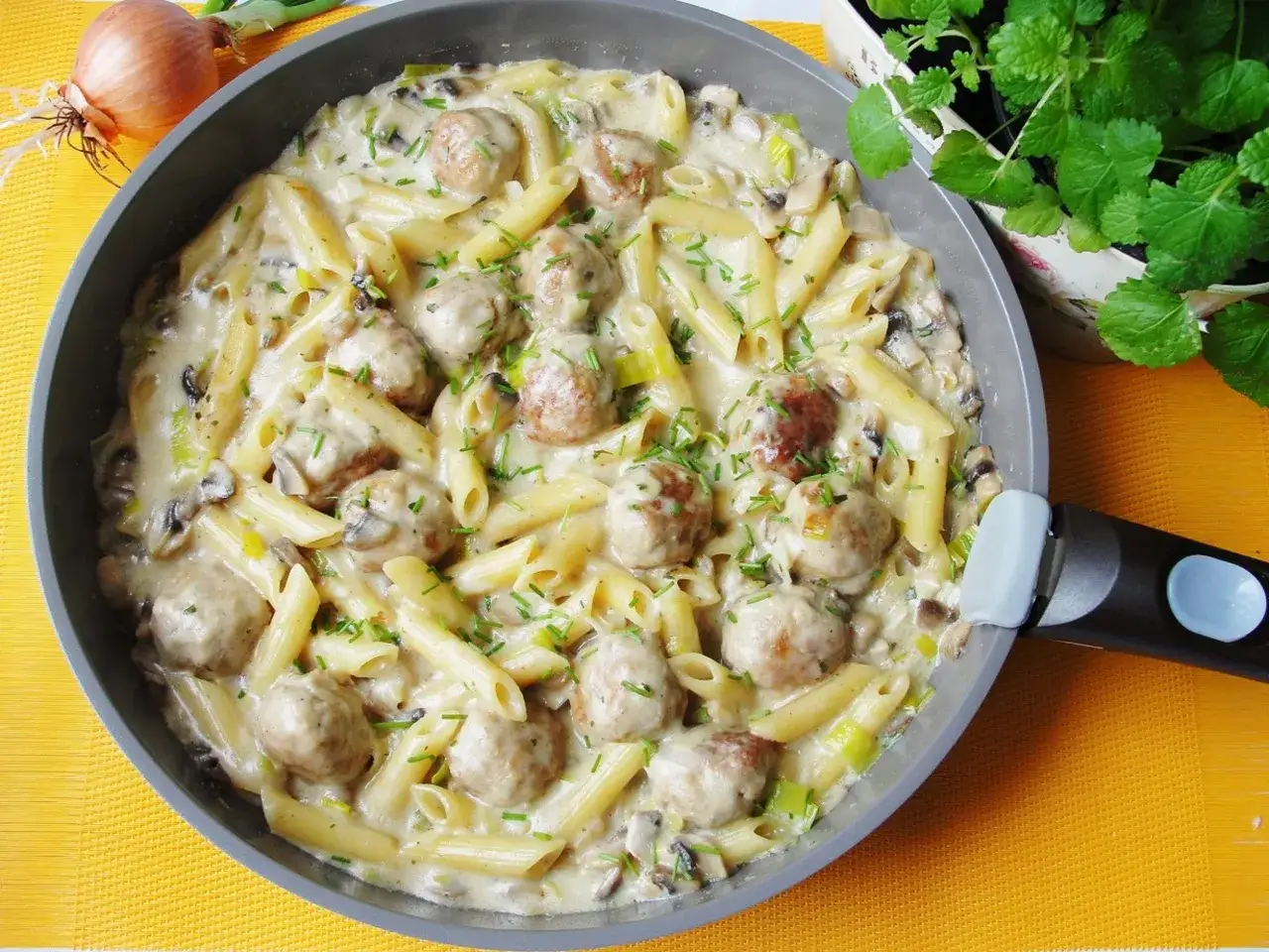 Szybki obiad dla dzieci: penne z klopsikami w kremowym sosie z pieczarkami i porem, posypane szczypiorkiem.