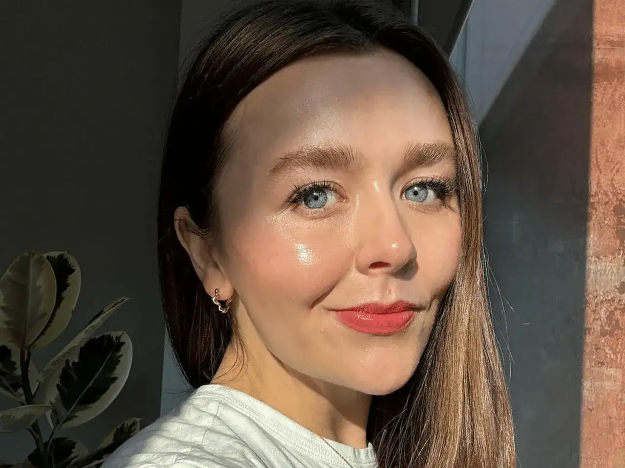 En kvinna med bl&aring; &ouml;gon och glansig hud ler. Solen lyser p&aring; hennes panna och framh&auml;ver hennes **finnar i pannan**.