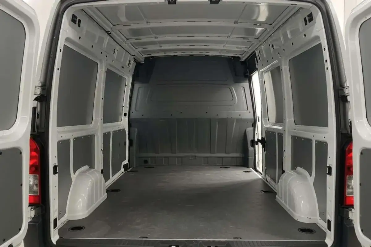 Vue int&eacute;rieure d'un fourgon blanc. Le plancher est gris fonc&eacute;, les parois sont blanches avec des panneaux gris. Les portes arri&egrave;re sont ouvertes. Id&eacute;al pour visualiser les renault master l2h2 dimensions int&eacute;rieures.