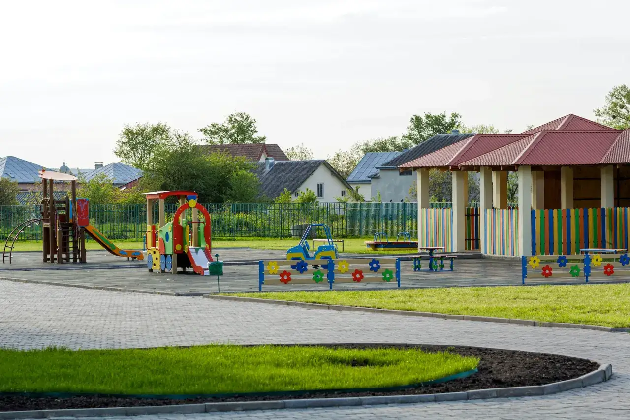 Kolorowy plac zabaw z domkami i zjeżdżalniami. Czy plac zabaw wymaga pozwolenia na budowę? Zależy od jego wielkości i przeznaczenia.