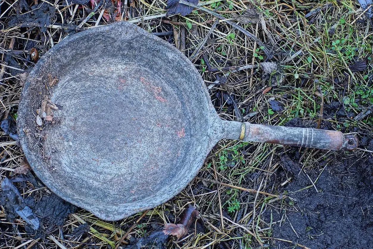 Stara, zardzewiała patelnia leży na ziemi. Zastanawiasz się, gdzie wyrzucić starą patelnię?