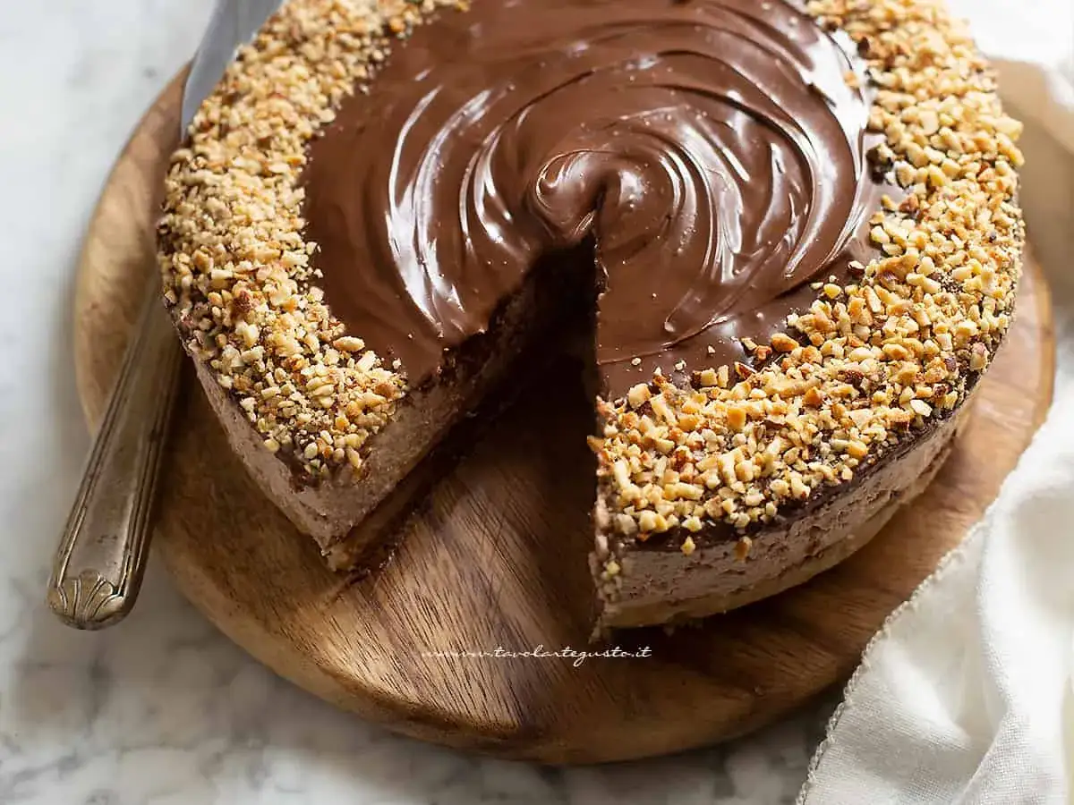 Cheesecake alla Nutella golosa, con copertura lucida al cioccolato e granella di nocciole croccante sui bordi.