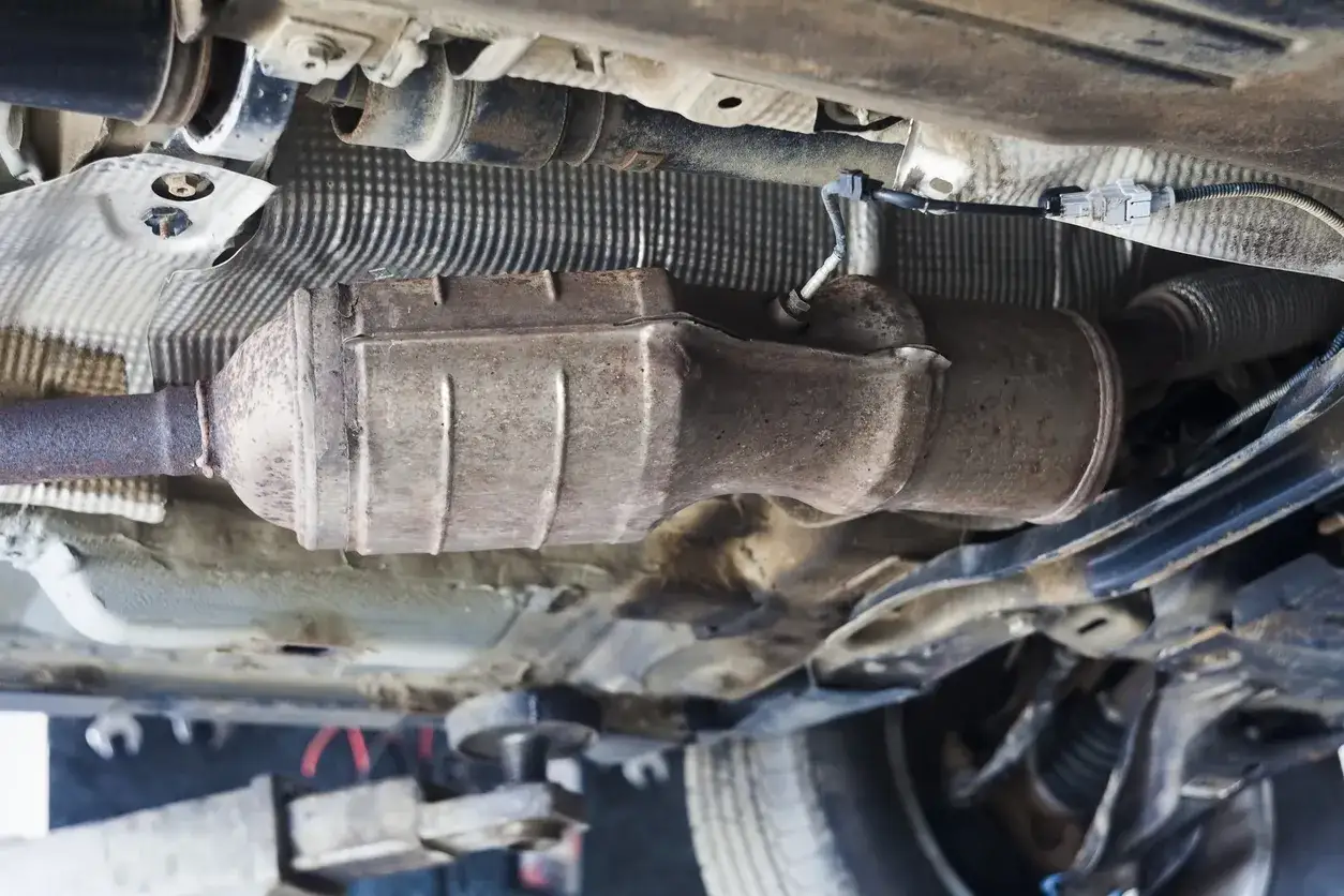 Vue du dessous d'une voiture, montrant le système d'échappement rouillé. Le filtre à particules est intégré dans ce système.