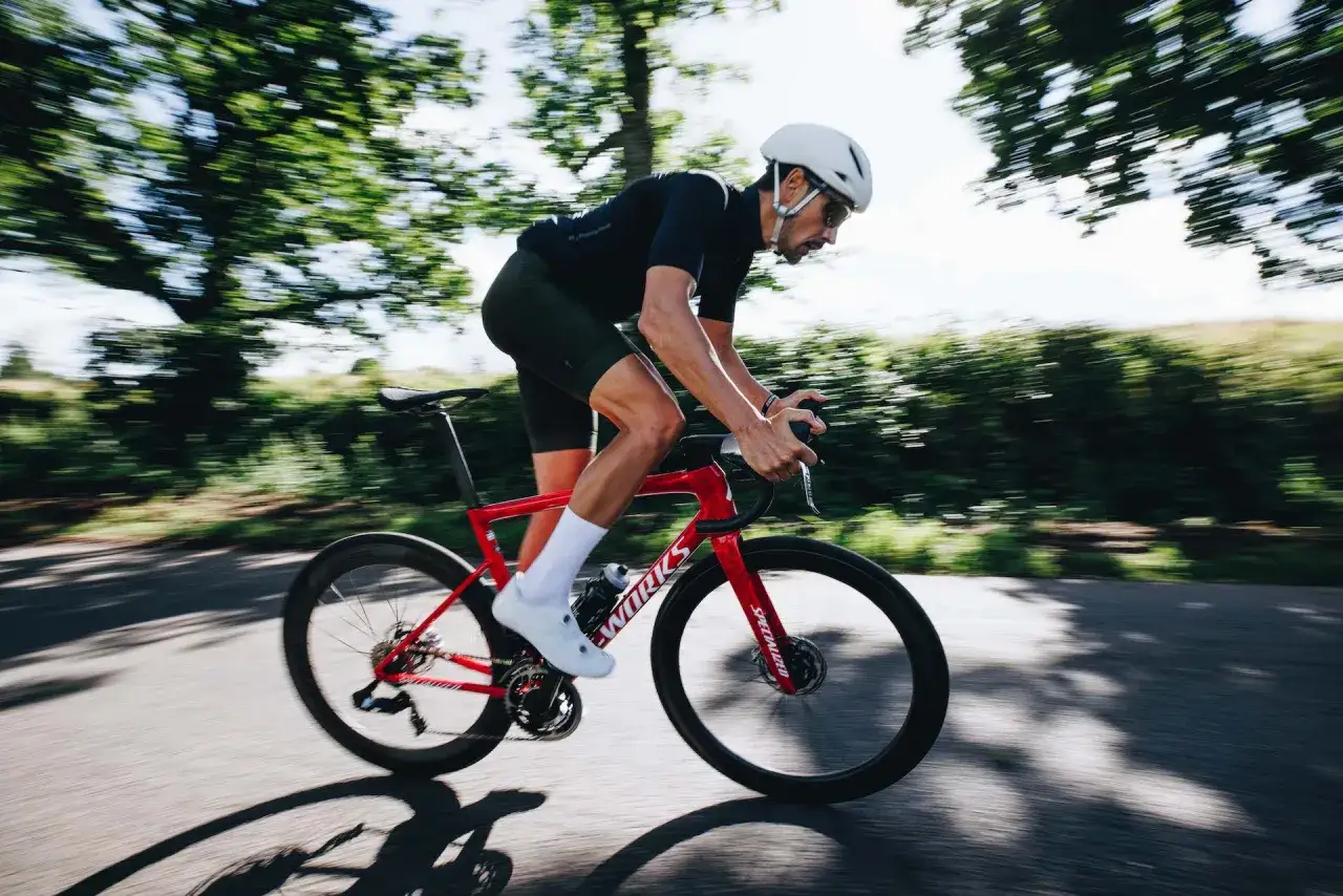 Kolarz w kasku i stroju kolarskim pędzi na czerwonym rowerze. Intensywny trening, jak tabata, daje mu siłę.