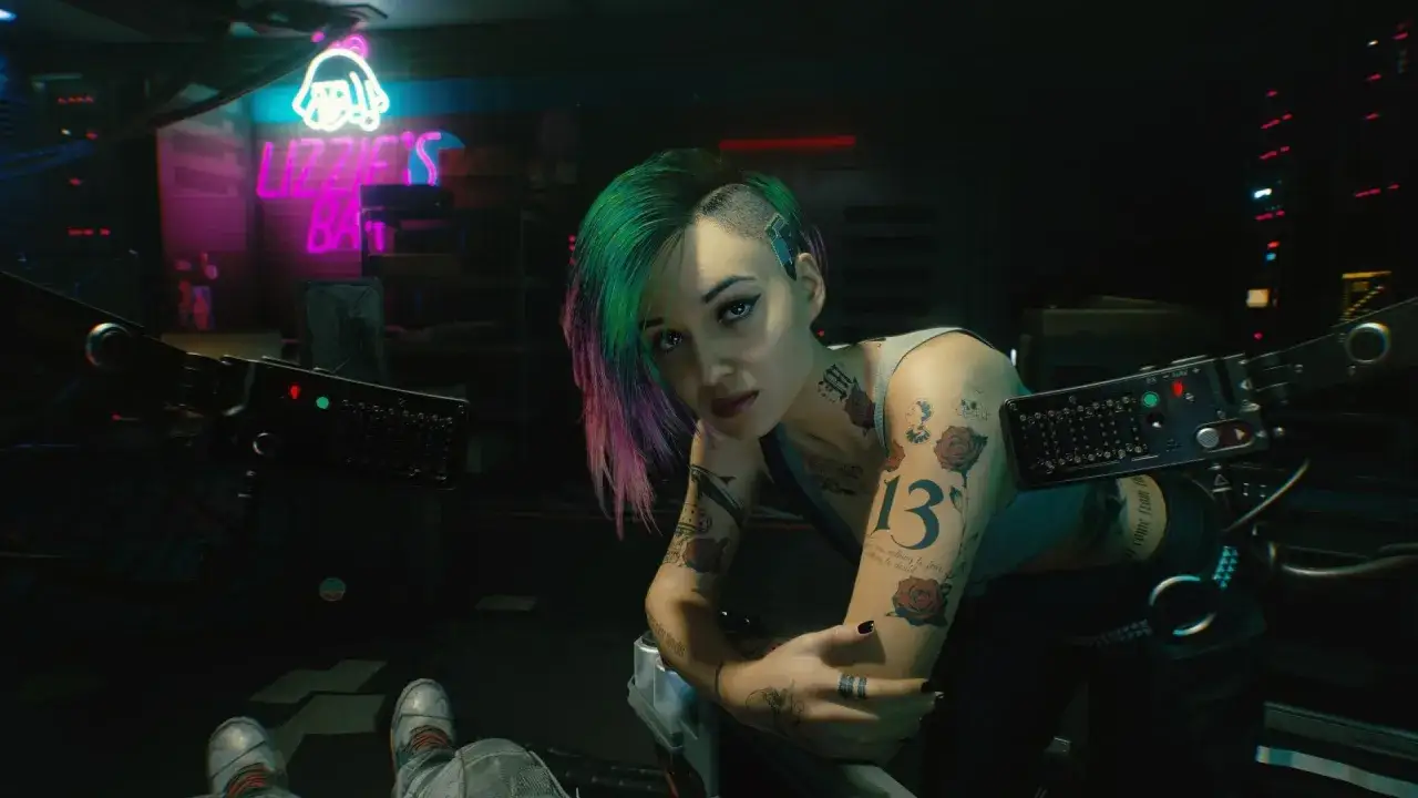 Cyberpunk 2077: Eine Frau mit bunten Haaren und Tattoos, die an Sex und Gefahr erinnert, sitzt in einer Bar.