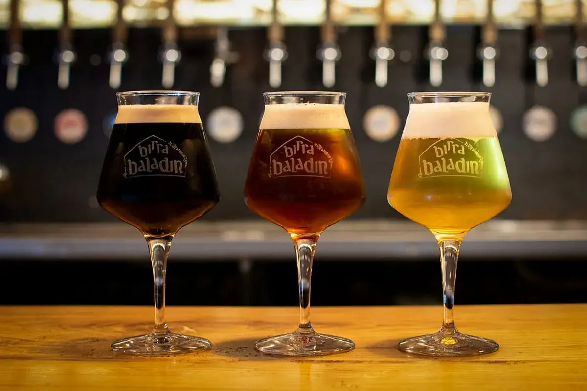Tre bicchieri di birra Baladin, uno scuro, uno ambrato e uno chiaro, con schiuma abbondante. Un bicchiere IPA perfetto per ogni gusto.