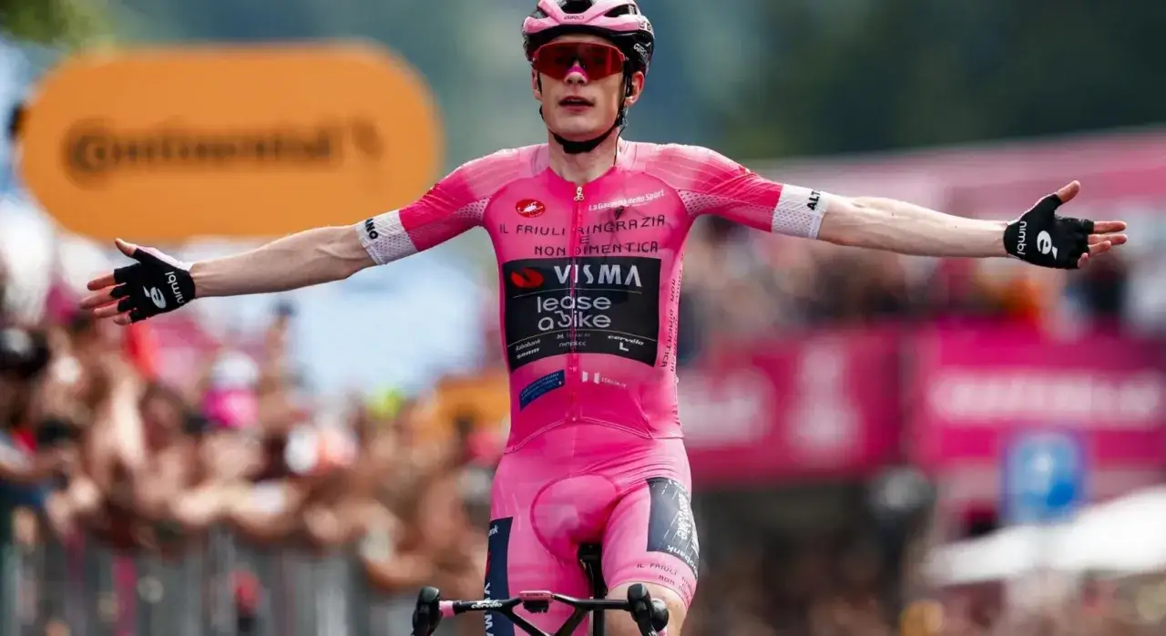 Cyclist in pink jersey with arms outstretched, celebrating his victory as he won the Giro d'Italia.