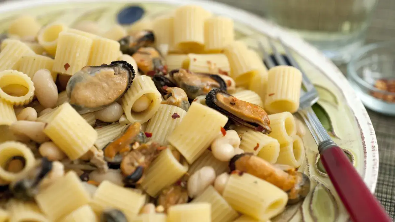 Un plato de pasta fagioli e cozze, con rigatoni, alubias blancas y mejillones, salpicado de copos de chile rojo.