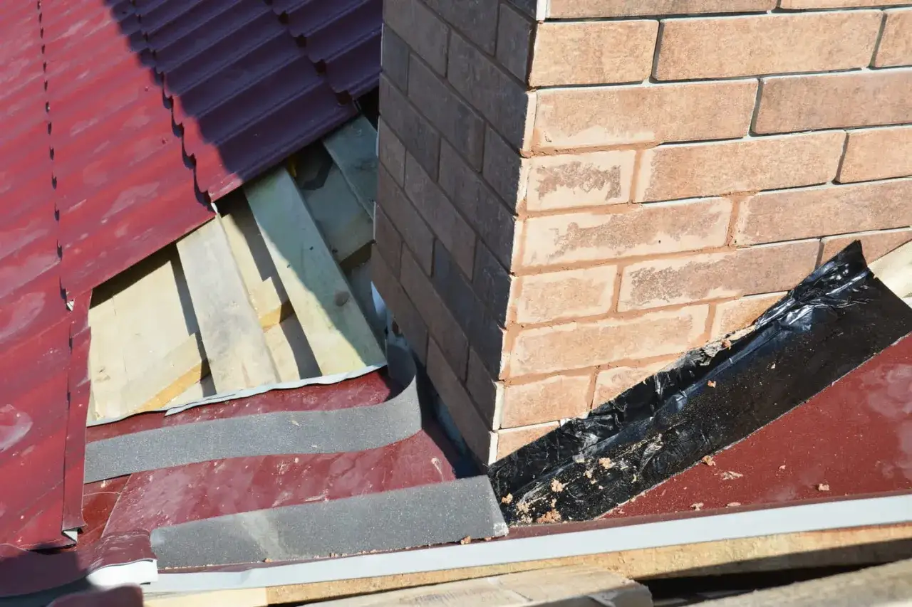 Travaux d'&eacute;tanch&eacute;it&eacute; chemin&eacute;e en cours sur un toit en tuiles rouges. Isolation et protection contre les intemp&eacute;ries.