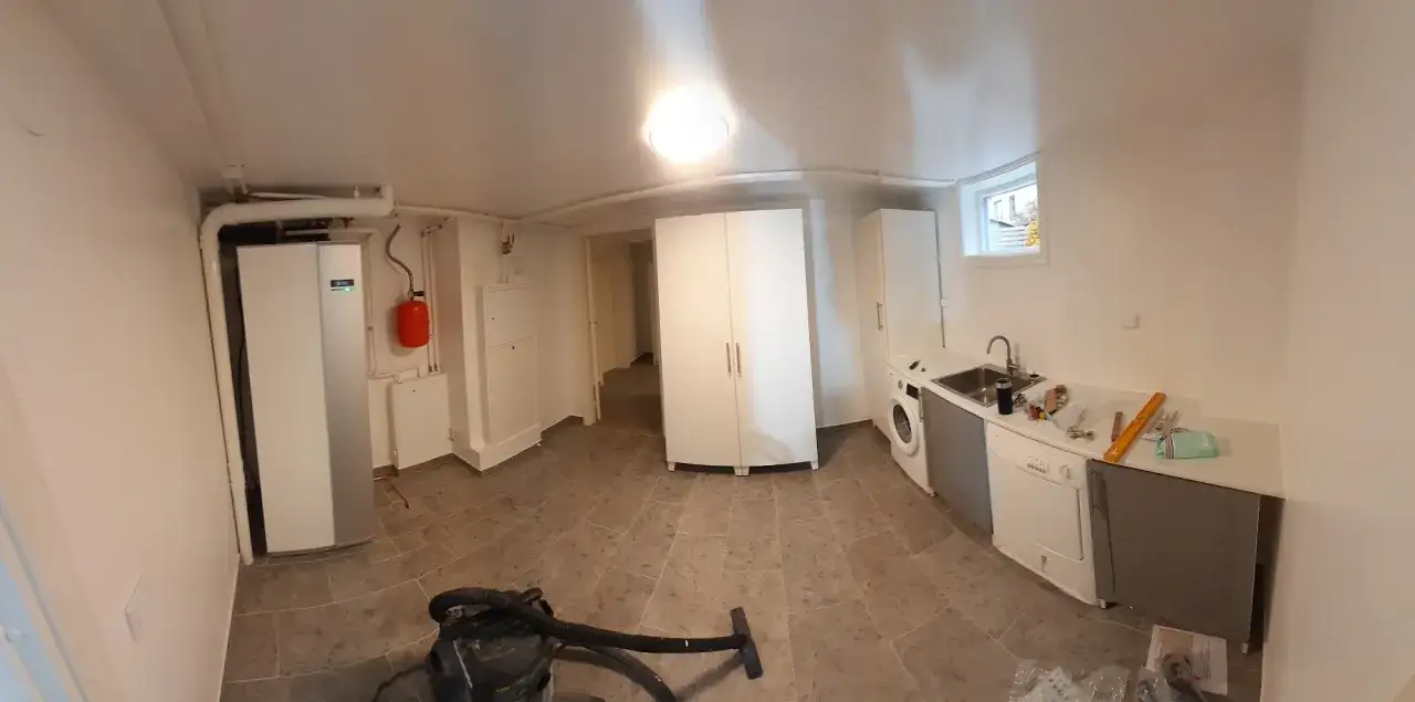 Renovering av tv&auml;ttstuga med ny varmvattenberedare och vitvaror. Golvet &auml;r nylagt, och man ser sp&aring;r av tidigare fuktskada i badrummet.