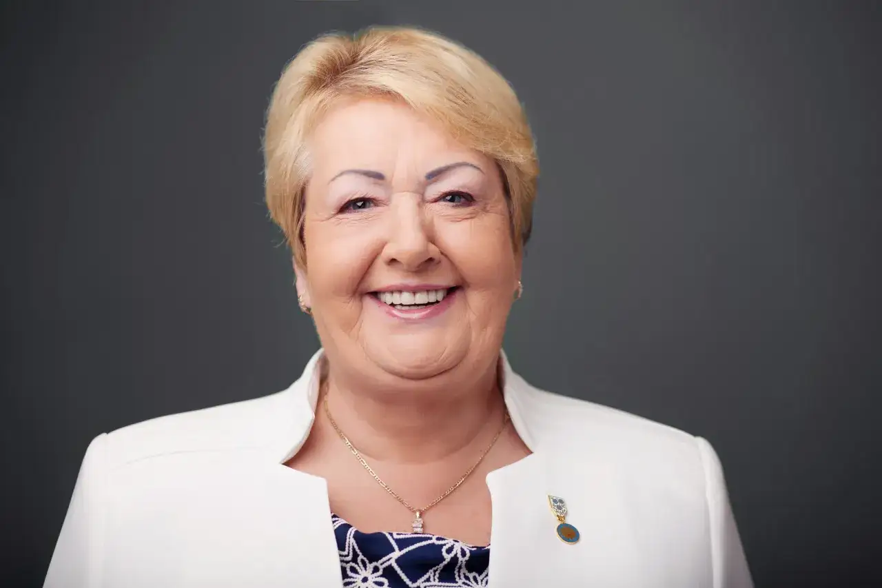 Uśmiechnięta Henryka Krzywonos Strycharska w białej marynarce z medalionem.