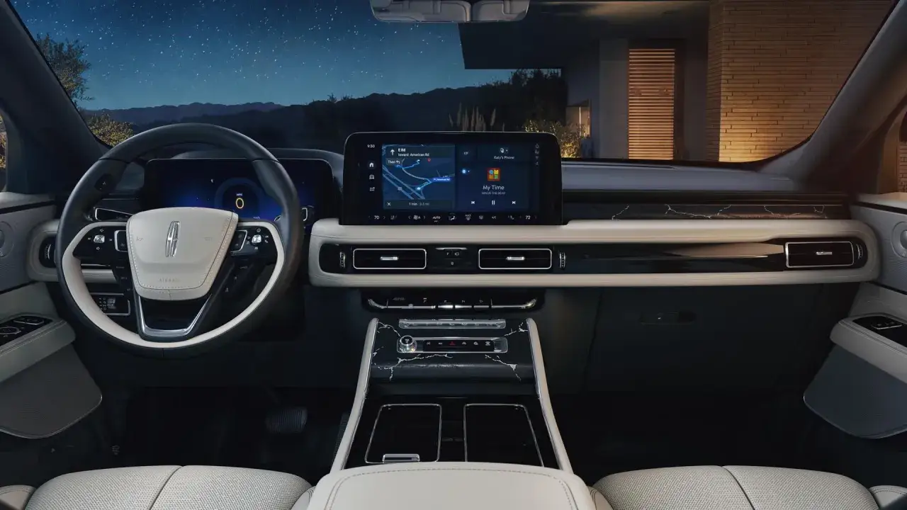 Wnętrze Lincoln Aviator nocą. Na ekranie nawigacja i muzyka. Luksusowe materiały i nowoczesny design.
