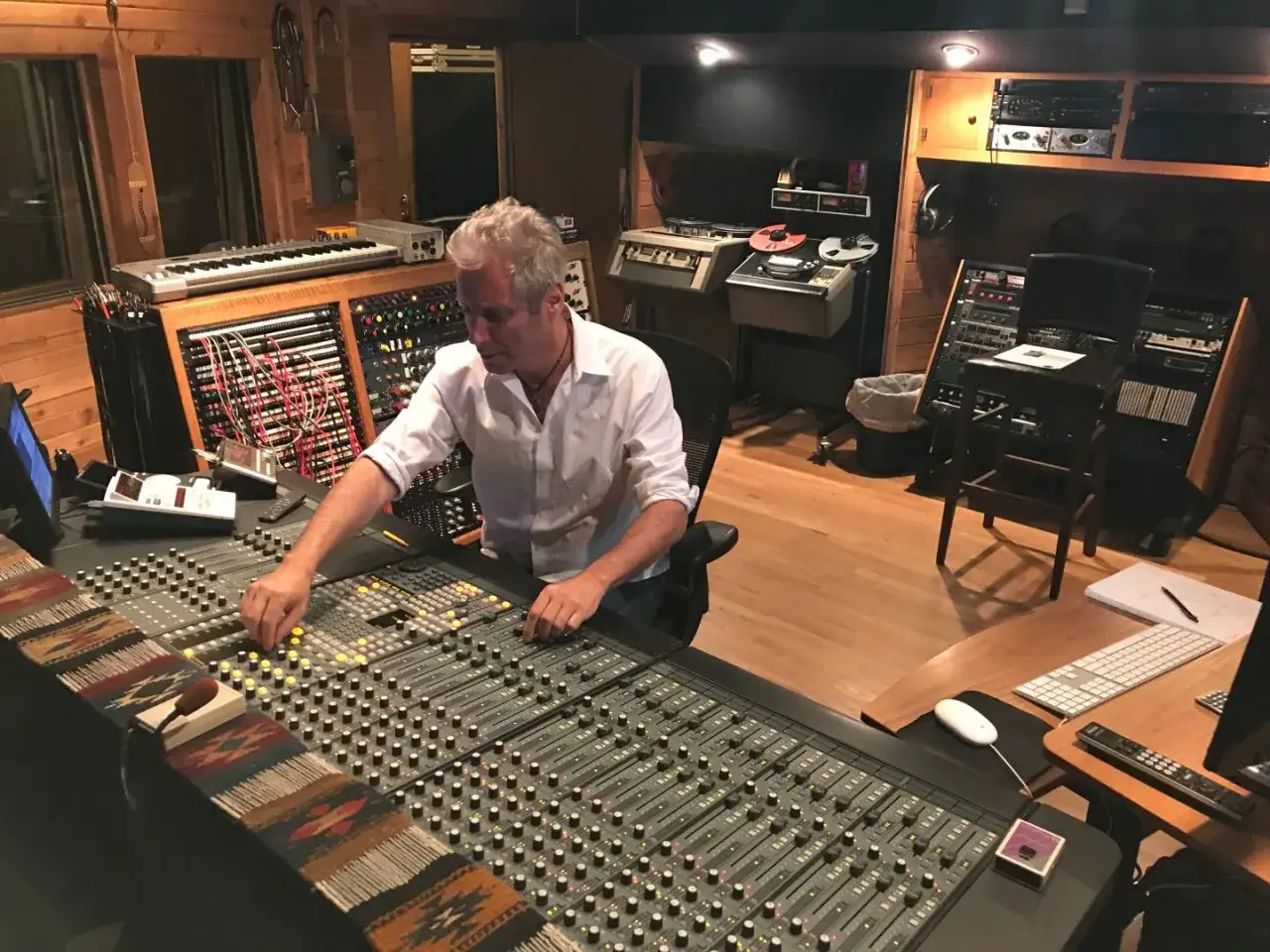 A music manager fine-tunes a mixing board in a professional recording studio, surrounded by vintage audio equipment.