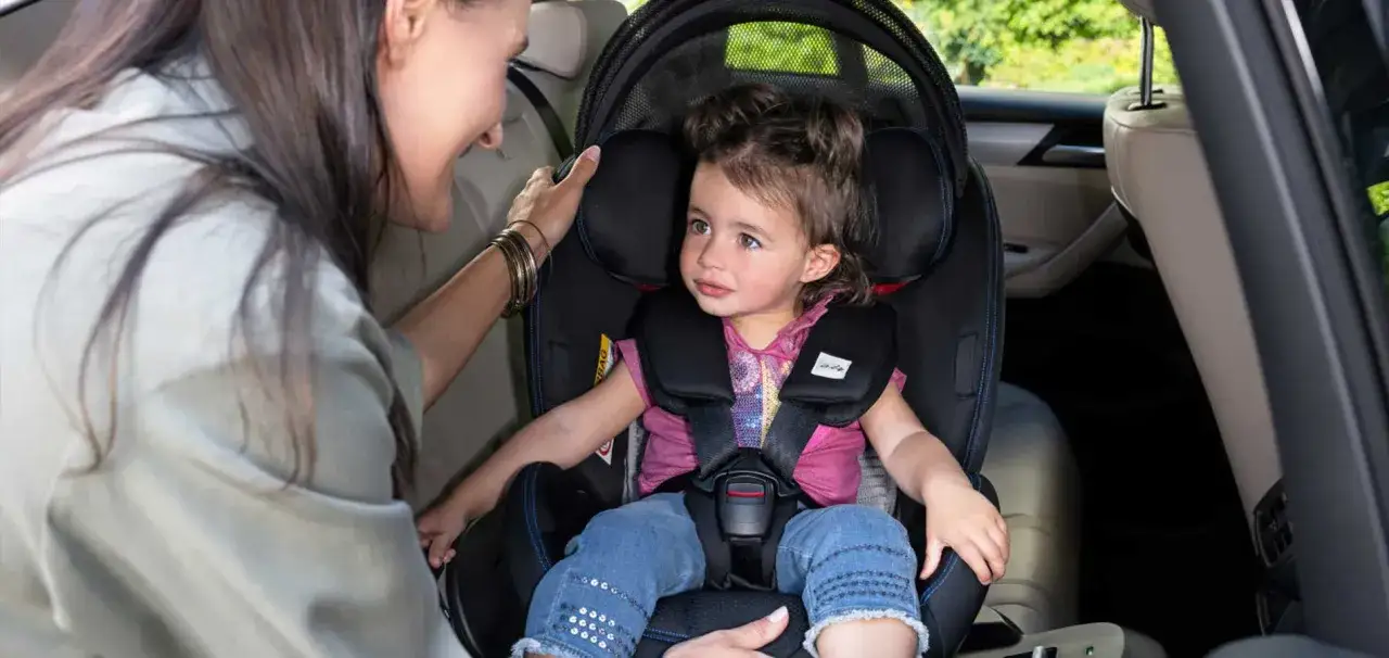Madre ajusta el arnés de seguridad a su hija, una de los niños en el coche, lista para el viaje.