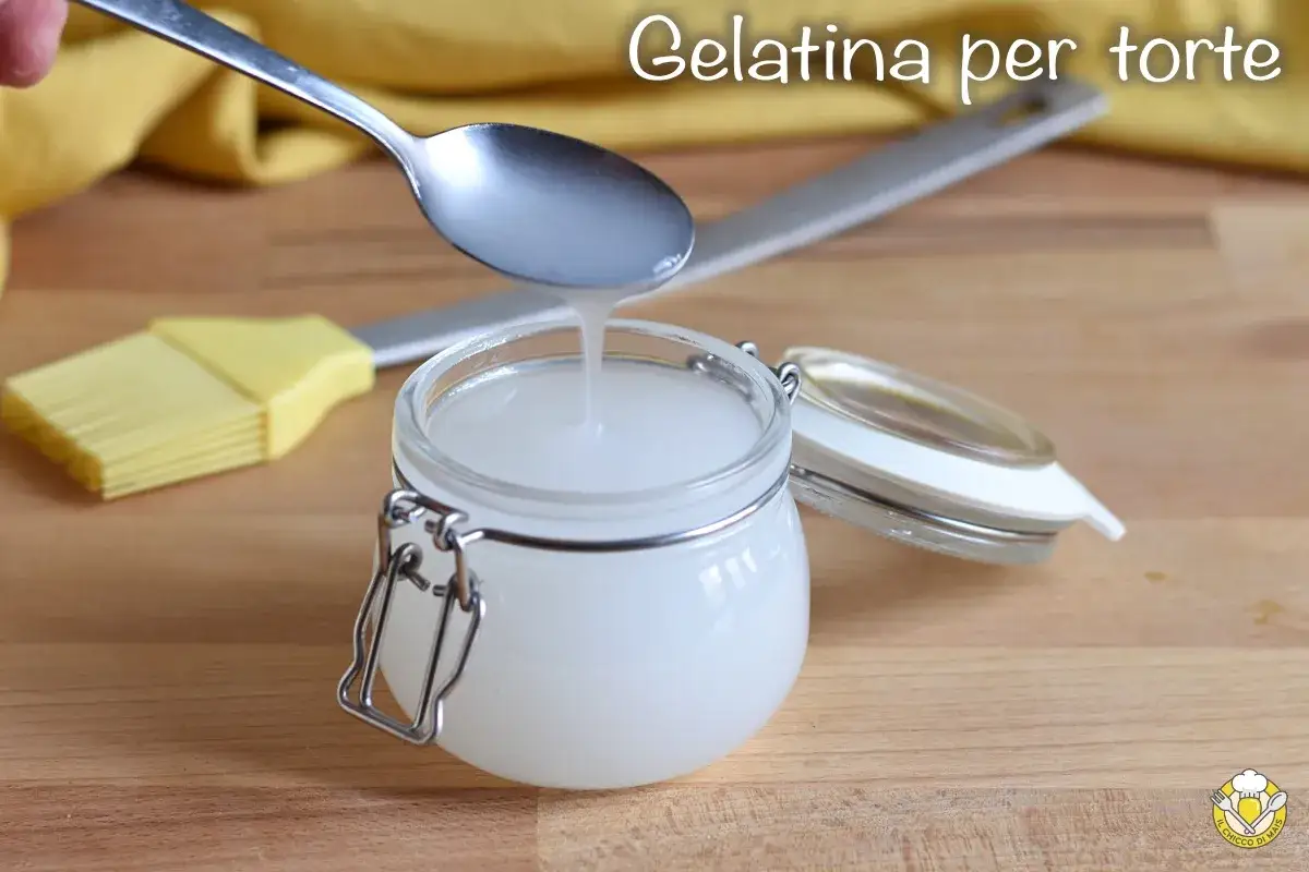 Gelatina per torte fatta in casa, lucida e trasparente, versata da un cucchiaio in un vasetto di vetro.