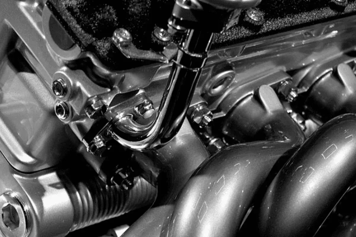 Gros plan sur un moteur de voiture essence, avec des tuyaux chrom&eacute;s et des boulons. On dirait que la voiture qui broute en roulant essence a un probl&egrave;me m&eacute;canique.