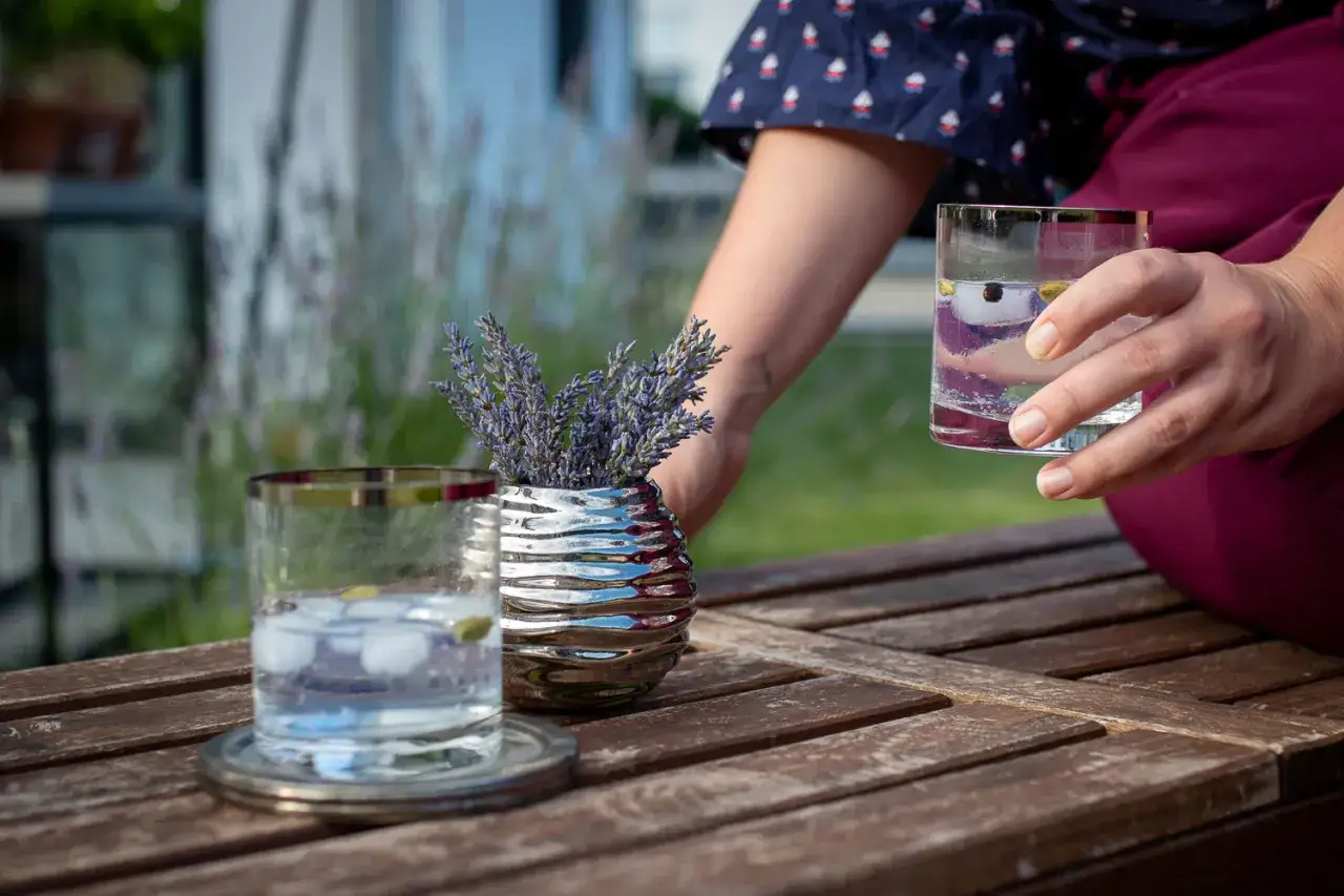 Erfrischender alkoholfreier Gin mit Eis und Beeren auf Holztisch, daneben Lavendel.