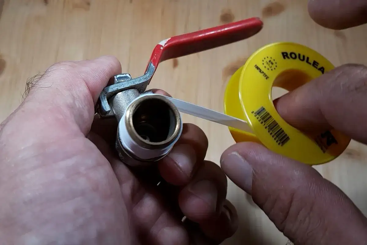 Main tenant une vanne, il applique du teflon sur le filetage pour assurer une étanchéité parfaite.