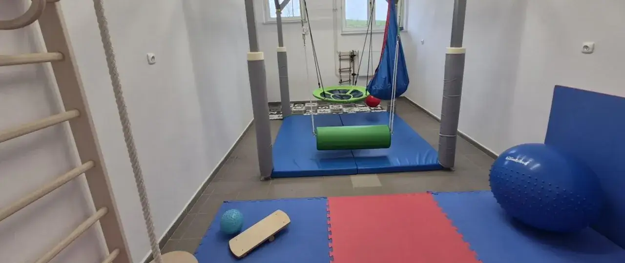 Sala do rewalidacji w szkole podstawowej: drabinki, huśtawki, materace i piłki do ćwiczeń wspierają rozwój dzieci.