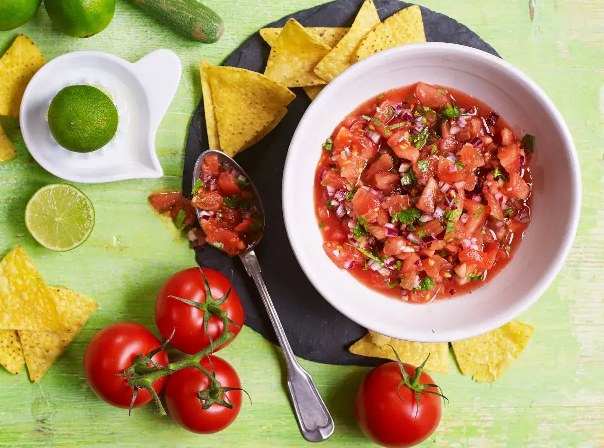 Świeża salsa pomidorowa z cebulą i kolendrą, podana z nachos i limonką. Idealna do meksykańskich przekąsek.