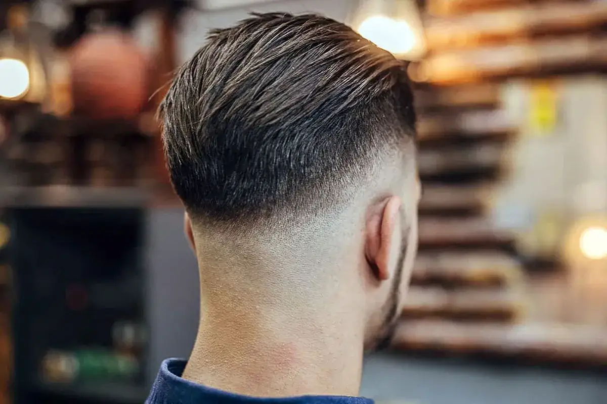 Eleganckie strzyżenie męskie tył głowy z efektem fade. Włosy zaczesane do g&oacute;ry, z subtelnym cieniowaniem przy karku.