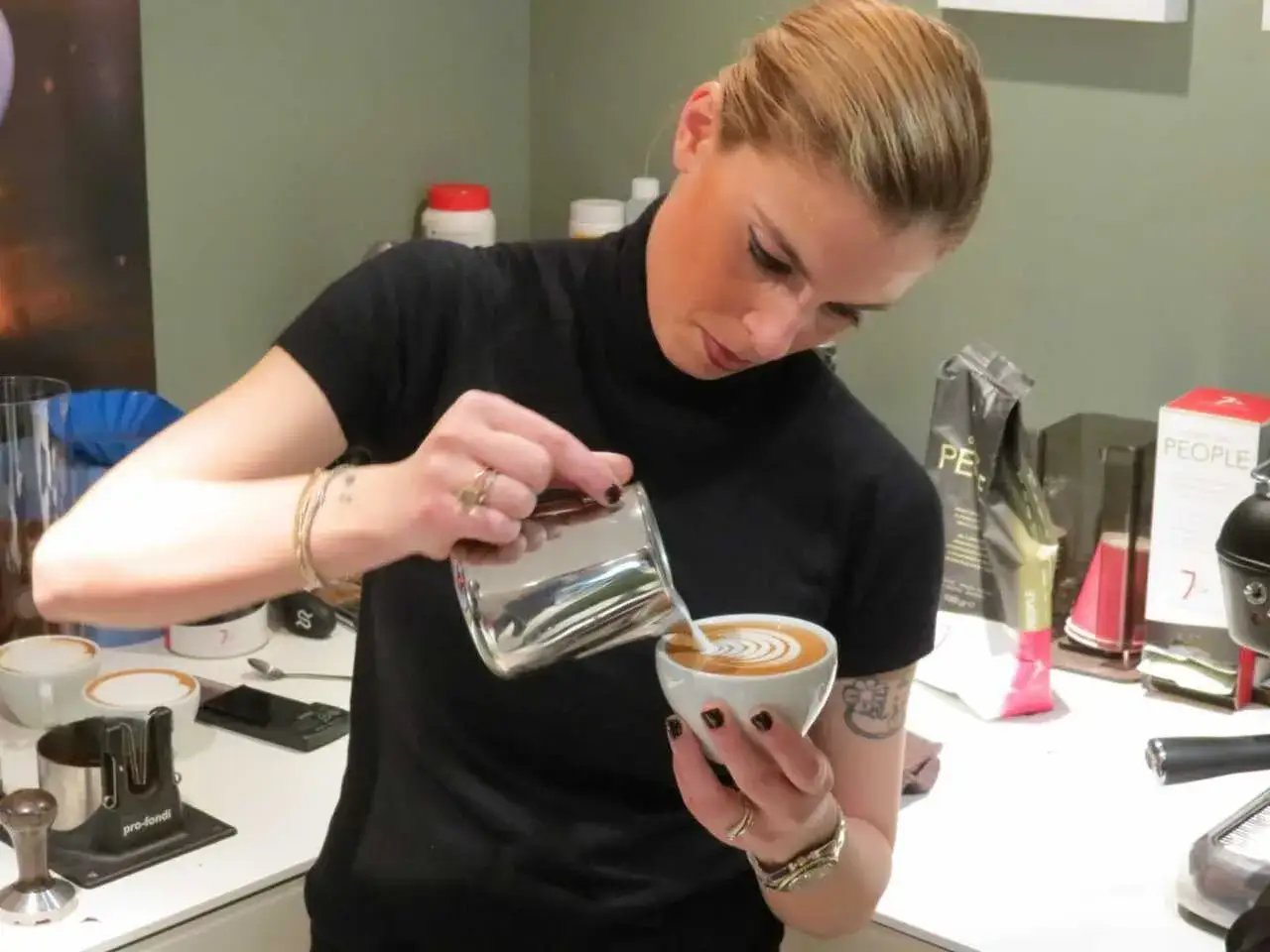 Chiara Bergonzi crea un disegno latte art con maestria, versando il latte montato in una tazza di caffè.