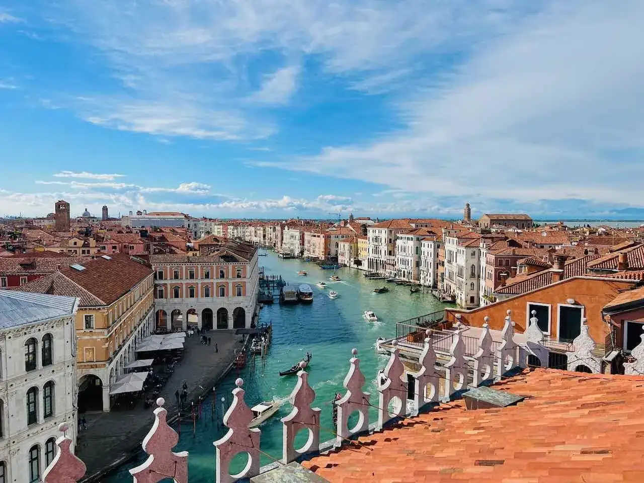 Ein perfekter Tag in Venedig: Blick &uuml;ber den Canal Grande mit Gondeln und Booten, umgeben von historischen Geb&auml;uden unter blauem Himmel.