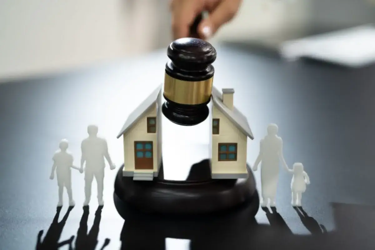 Marteau de juge sur une maison divis&eacute;e, symbolisant un couple non cohabitant probl&egrave;me. Des silhouettes de famille se tiennent de chaque c&ocirc;t&eacute;.