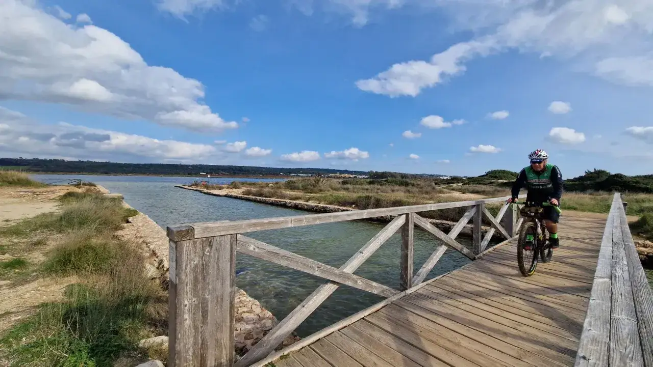 Ciclista su un ponte di legno, esplorando le bellezze naturali di Ugento. Un'ottima idea per scoprire cosa vedere!