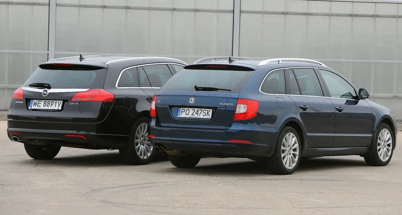 Dwa kombi: czarny Opel Insignia i niebieska Skoda Superb, która jest największym kombi na rynku, stoją obok siebie.
