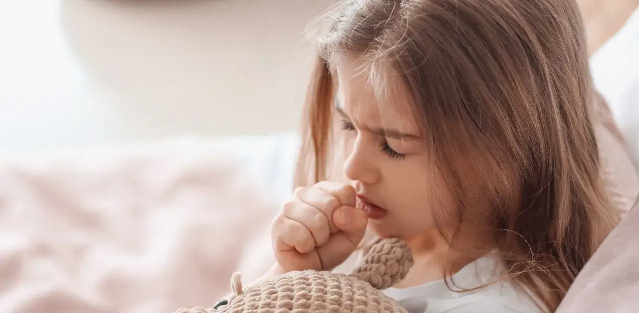 Mała dziewczynka z zabawką, która męczy się z powodu kaszlu w nocy.